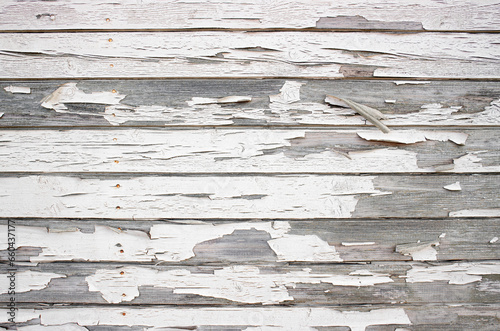 Rough crackled paint on wooden boards, white color paint peeling off, horizontal wood boards.