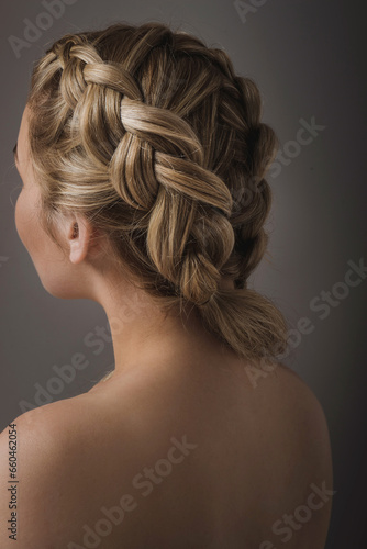 Close-up of a blonde woman's hairstyle, back view from the back on a gray background