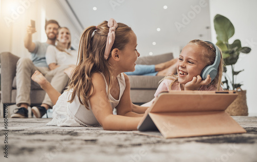 Happy kids on floor of living room with tablet, headphones and watching video, movie streaming or music. Digital game, online app and girl children relax on carpet together with fun in family home.