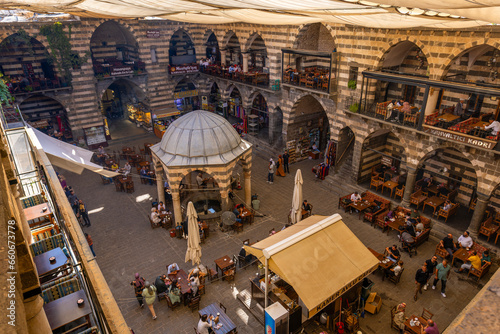 DIYARBAKIR, TURKEY, 05 OCTOBER 2023: View of the Hasanpasa Khan, medieval historic building where people have breakfast and small shops, the central of Diyarbakir,