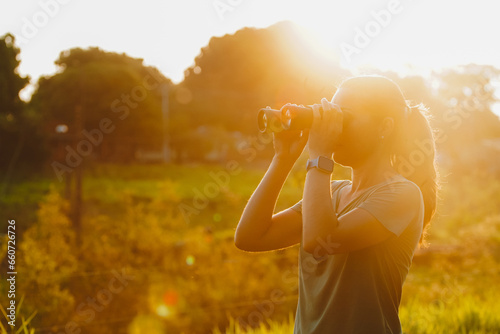 Woman looking through binoculars at the nature of Brazil. Beautiful sunset view of the Pantanal, Bonito, in Mato Grosso do Sul.