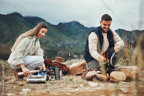 Couple, camping and fire in nature, mountains and outdoor for sustainable heating, vacation and prepare kettle. Happy man and woman in field with water, campfire or flames for cooking on holiday
