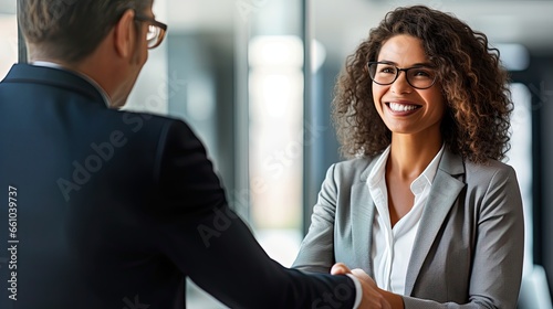 Happy mature Latin business woman manager or lawyer handshaking client at office meeting. Smiling professional businesswoman and businessman shake having partnership agreement with handshake