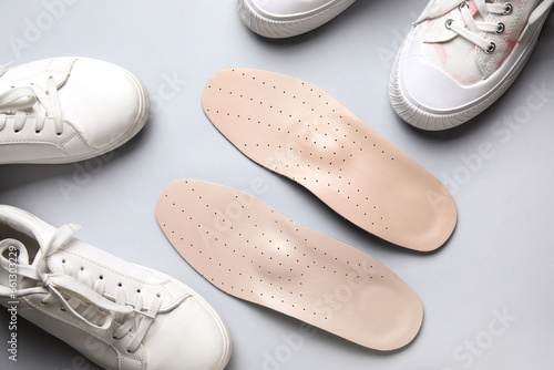 Pair of orthopedic insoles and stylish female shoes on light background, closeup