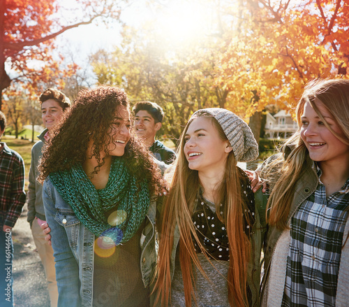 Teenager, walking and talking with friends in park, nature or social group outdoor in autumn with diversity. Happy, youth or kids relax in fall with a joke, best friend or conversation in community