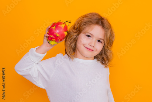 Dragon fruit. Kid hold dragon fruit in studio. Studio portrait of cute child with dragon fruit isolated on yellow background, copy space.