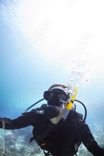 Person, swimming and scuba diving in ocean to explore underwater, adventure and tropical holiday or vacation. Expert diver in Maldives with mockup space, nature and bubbles in water for sea life
