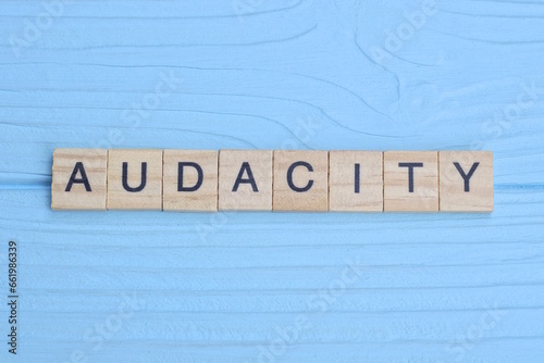 word audacity made from wooden gray letters lies on a blue background