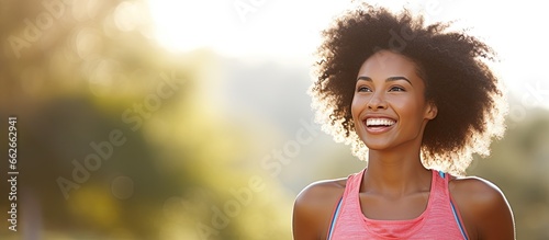 A joyful African American woman smiling while taking a break from her outdoor run enjoying nature and staying fit With copyspace for text