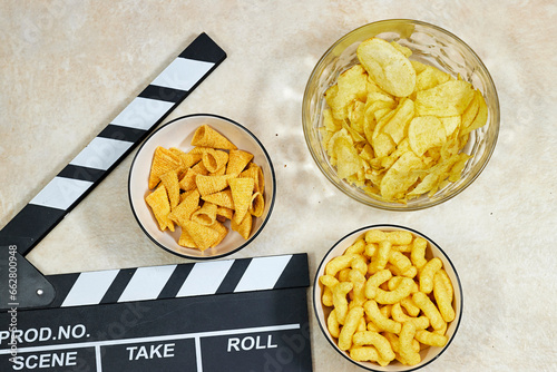 clapper board of video cinema in studio and bowls of different chips on grunge background 