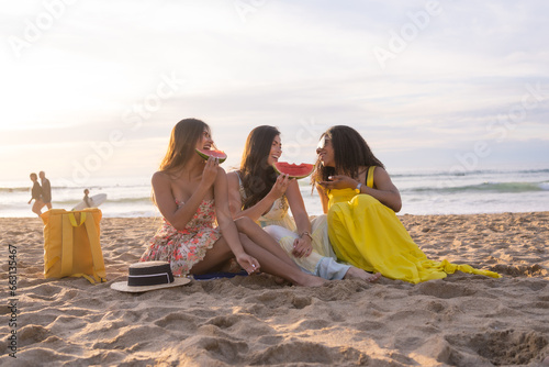 Multi-ethnic women enjoying together eating watermelon in the beach