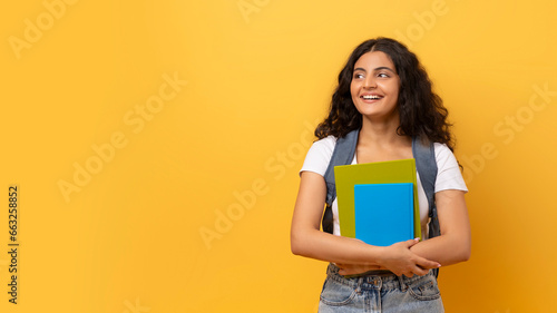 Young smiling happy indian woman student on yellow