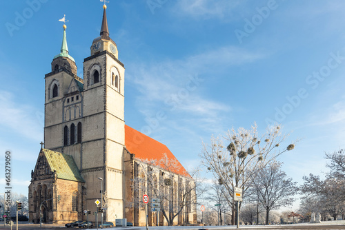 Scenic view of old St John Church in Magdeburg old city center against blue sky on cold frosty winter day. Snowy sunny german cityscape with ancient cathedral. European travel destination