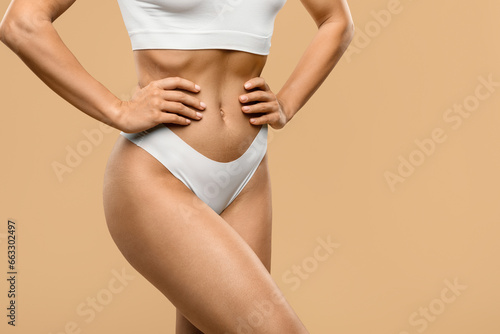 Young Slim Sporty Female Body In White Underwear Over Beige Background, Cropped