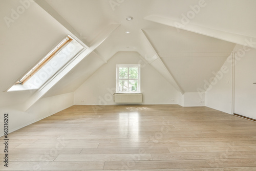 an empty room with wood floors and skylights in the corners on the right side of the room, there is a window