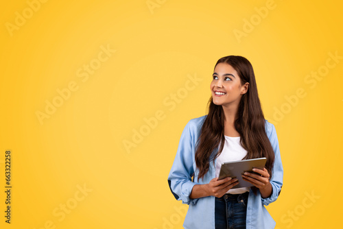 Teen student using tablet, blending study and tech in a yellow-themed lifestyle