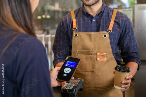 Man owner coffee shop submit an electronic cash register and coffee cup to woman customer, Female use phones scan payments through banking apps to pay for food and drink. pay with credit card.