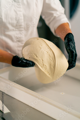 close-up of female hands in gloves putting dough into a bread shape on baking sheet for baking fresh pastries