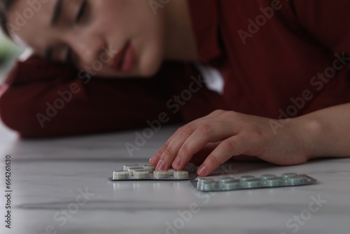Woman with antidepressant pills sleeping at white marble table, selective focus