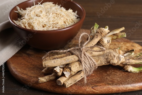 Grated horseradish and roots on wooden table, closeup