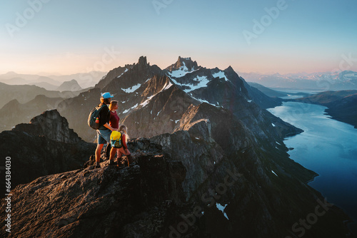 Travel adventures in Norway: family hiking in mountains outdoor parents and child on the top enjoying Kvaloya landscape active healthy lifestyle vacations mother and father with kid eco tourism