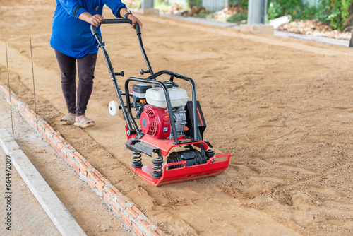 Worker use vibratory plate machine compactor for construction compacting.