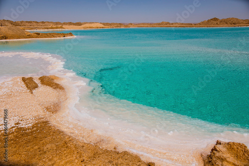 Salt lake with turquoise water and white salt on the shore near Siwa oasis, Egypt