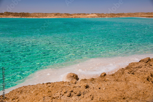 Salt lake with turquoise water and white salt on the shore near Siwa oasis, Egypt