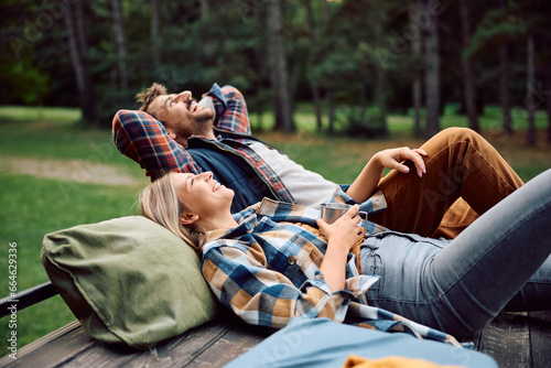 Happy couple of campers enjoying in freedom and fresh air in woods.