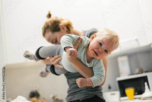 That awkward moment when your mom sniffs your butt. Mother holding her baby, sniffing stinky diaper of her little boy checking if it is time to change it