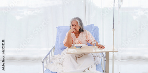 Asian elderly woman sick gastritis gastrointestinal disease enter hospital eating bland food porridge doesn't taste good lose your appetite sit look food bowl tired recuperating and sleeping hospital.