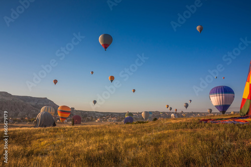 Hot air balloons take off from the ground early in the morning. Hot air balloons flying over bizarre rock landscape in Cappadocia. Beautiful hot air balloons in the morning sky. Goreme. Turkey