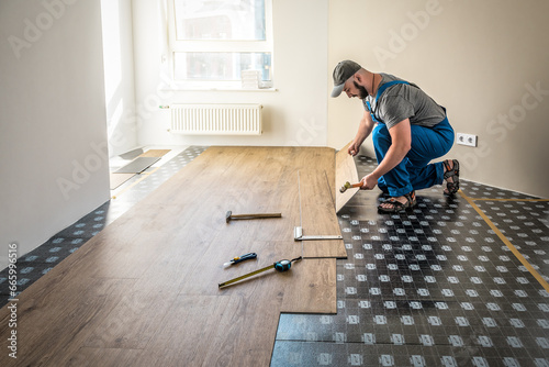 Professional worker joining vinyl floor covering at home renovation