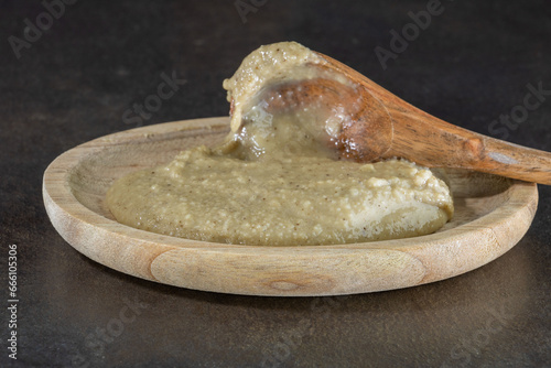 anchoïade, purée d'anchois à la crème, dans une assiette en bois avec une cuillère en bois d'olivier sur fond foncé gros plan rapproché. cuisine méditerranéenne pour dips