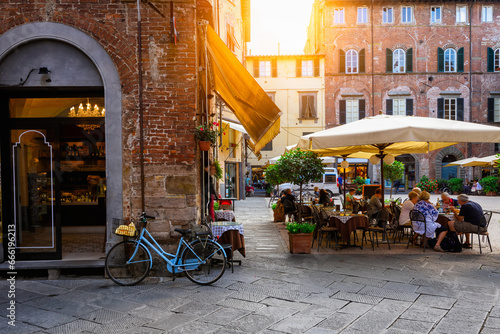 Old cozy street with tables of restaurant in Lucca, Italy