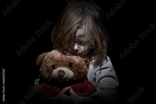 Sad little girl embracing her teddy bear - feels lonely - if you are small girl teddy bear is willing to be your best friend - vintage filter applied
