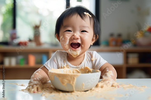 Cute little baby girl with a candid expression smiling at the camera with her face covered in porridge
