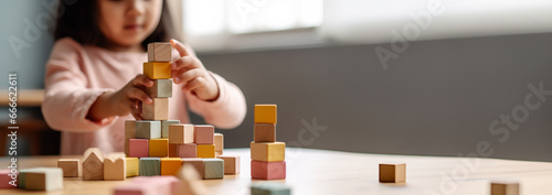 Kid playing with colorful wooden toy blocks. Little boy or girl building tower of block toys. Educational and creative toys and games for young children. Baby in white bedroom Copy space