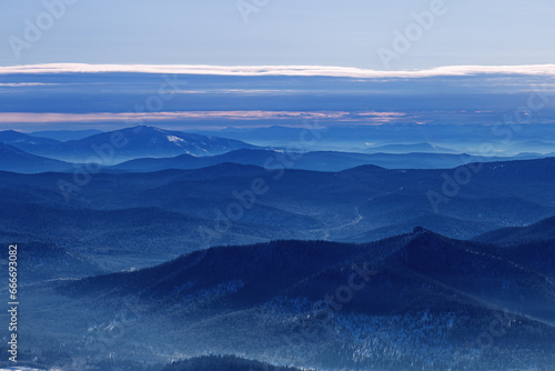 Winter nature panorama of far away blue mountains, picturesque view, aerial tonal perspective, monochrome photo of range mountains and blue sky, hills covered forest, great landscape in Altai