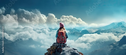 A happy girl in a turquoise helmet and windbreaker sits atop a mountain the traveler achieved their climb