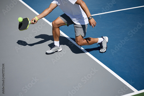 An athlete playing pickleball on a blue and gray court