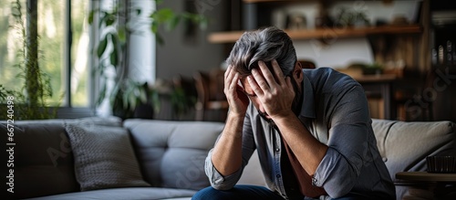Exhausted man in living room experiencing mental health issues including depression anxiety and financial problems resulting in frustration and despair