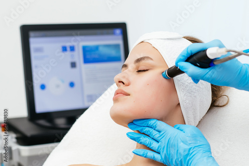 Close-up shot of a young beautiful woman lying on a couch in a cosmetology center. Young woman doing hydrofacial therapy in beauty spa.