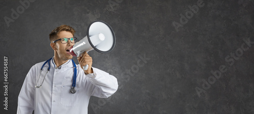 Male healthcare professional loudly announces important information through loudspeaker. Doctor on gray background near free space for text. Concept of medical marketing and sales. Banner.