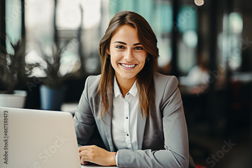 Jeune femme souriante assise a son bureau devant un ordinateur