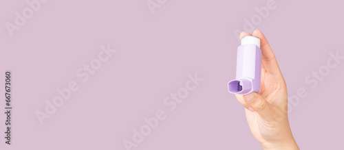 Hands holding asthma inhaler on purple background. Pharmaceutical product is used to treat lung inflammation and prevent asthma attack for asthma or COPD patients. Health and medical concept.