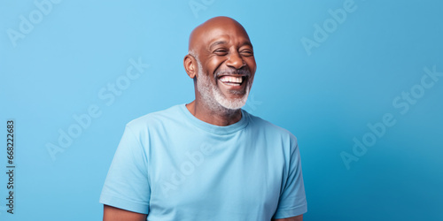 Blue november happy afro senior bald headed white bearded man wearing a light blue t shirt on blue background