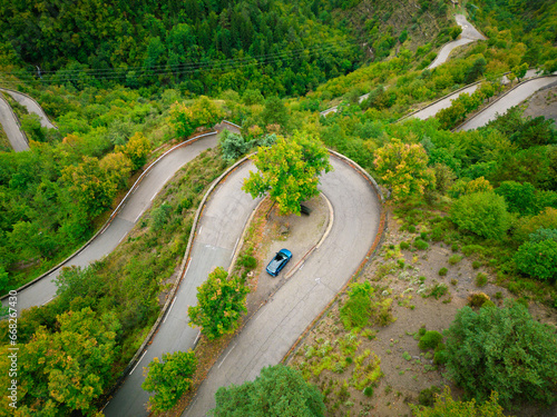 View from drone to Col de Turini, french alps pass. Foggy rainy day on a mountains. Curvy tarmac road.