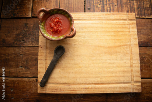 Foto horizontal cenital de una tabla de picar de madera con una cazuela mexicana con salsa comida típica mexicana para fondo o textura de comida
