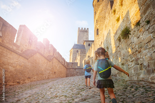 Kids hurry to explore Carcassonne castle walls at summer sunset